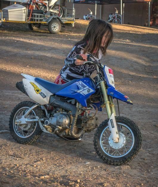 Little girl pushing a small dirtbike
